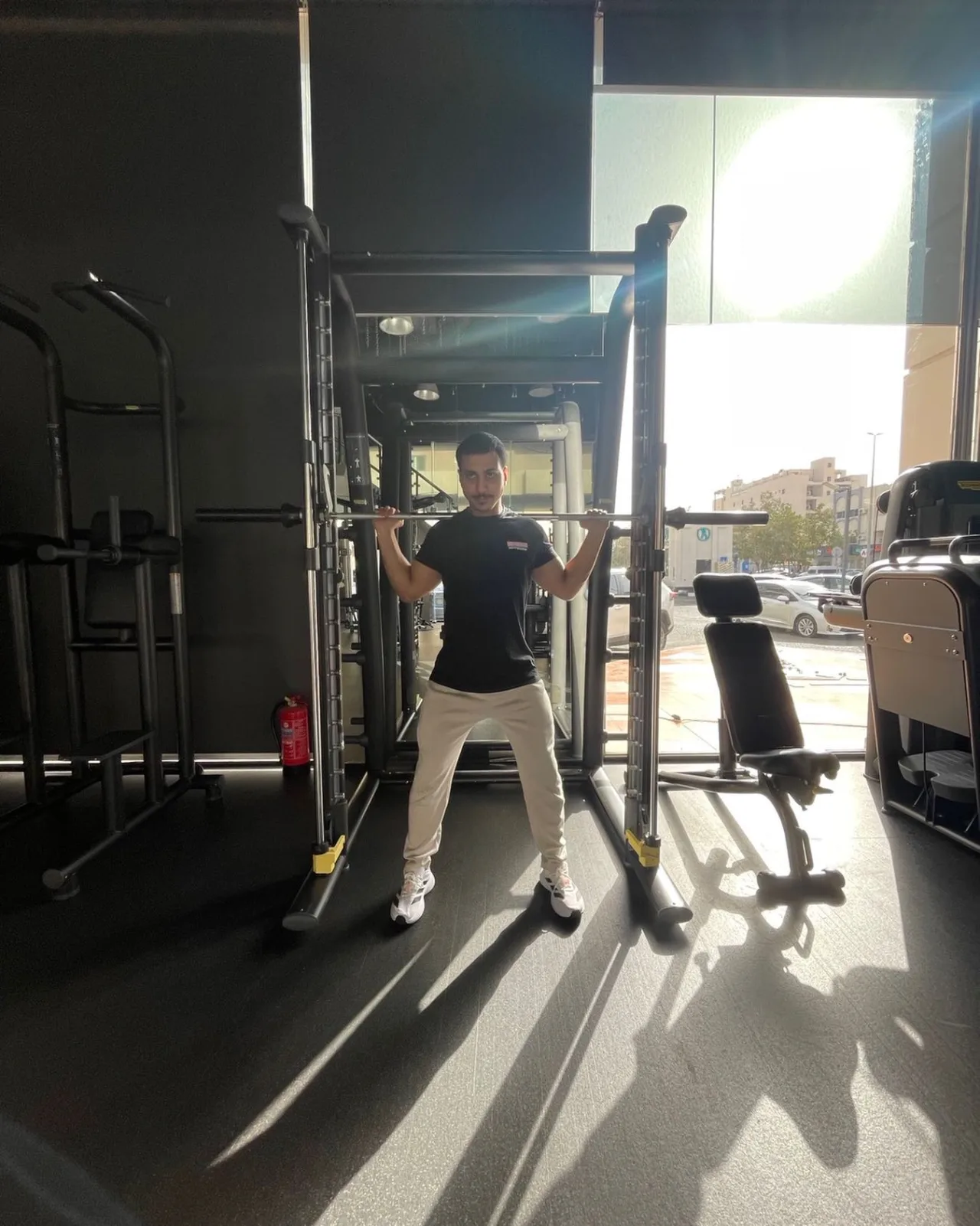 متدرب يقف أمام جهاز بار داخل My Gym مع ضوء النهار من الواجهة